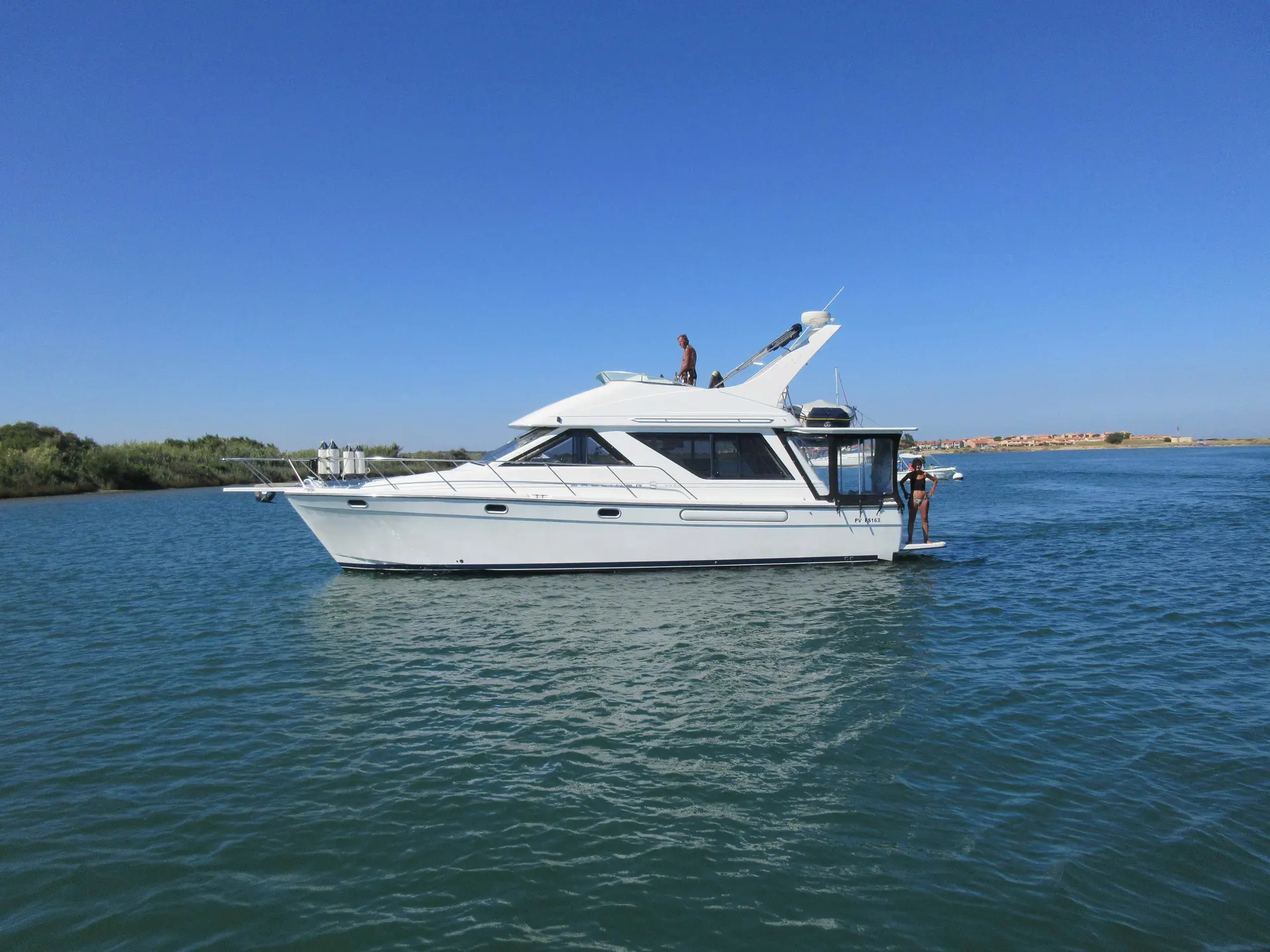 Bayliner 3988 — Bateau à moteur blanc vu de profil sur un plan d’eau, avec deux personnes à bord.