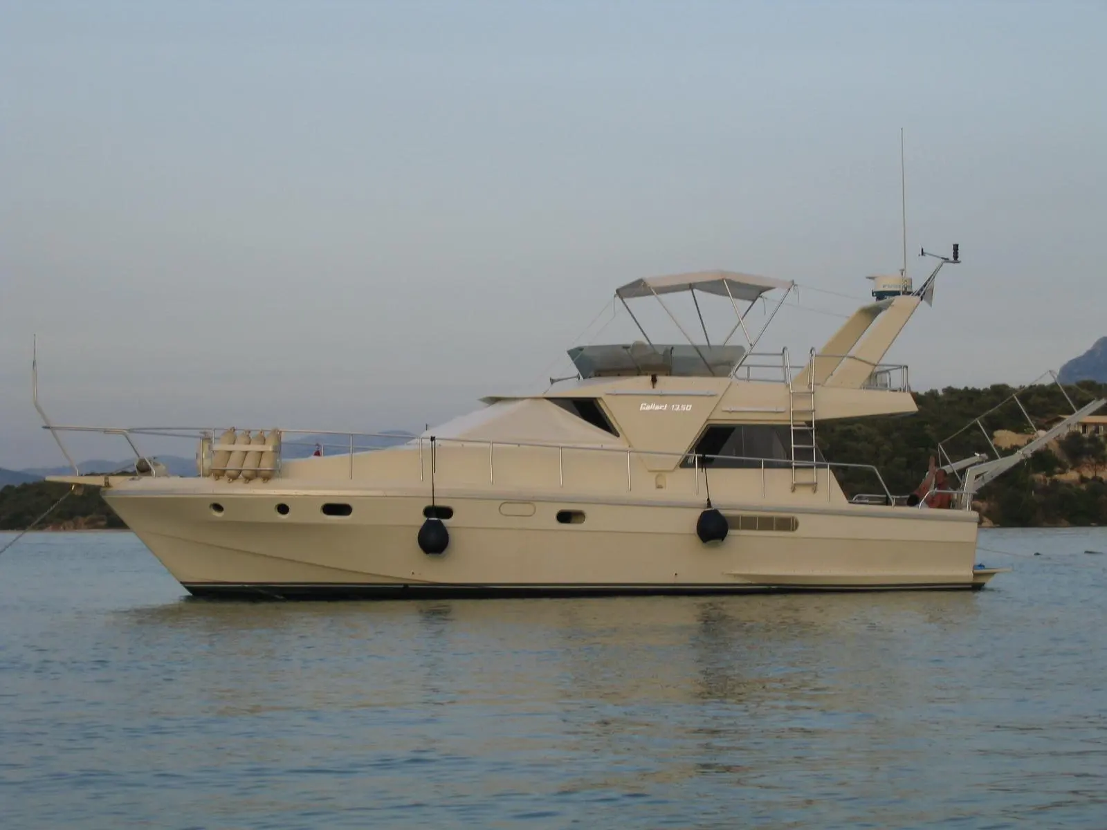 Gallart 1350 — Yacht à moteur beige photographié de profil sur une étendue d’eau.