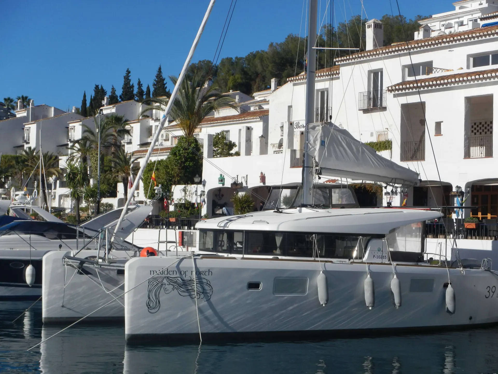 Lagoon 39 — Catamaran amarré, vu de profil, devant des bâtiments blancs en bord de port.