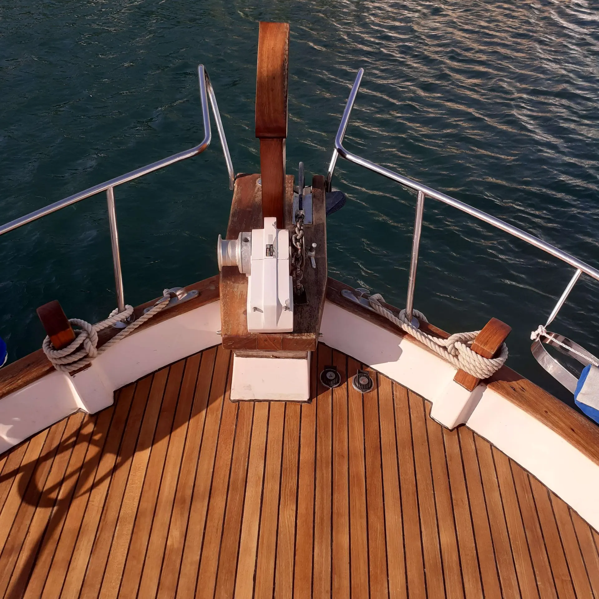 Menorquin 55 — Vue plongeante sur la proue en teck et l’ancre du bateau.