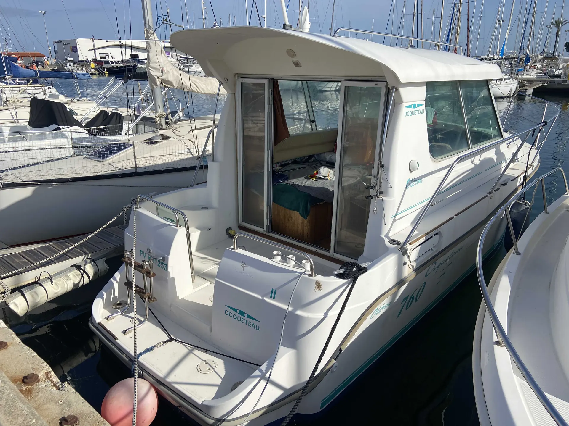 Ocqueteau 760 — Bateau à moteur blanc amarré dans un port, vu de trois quarts arrière.