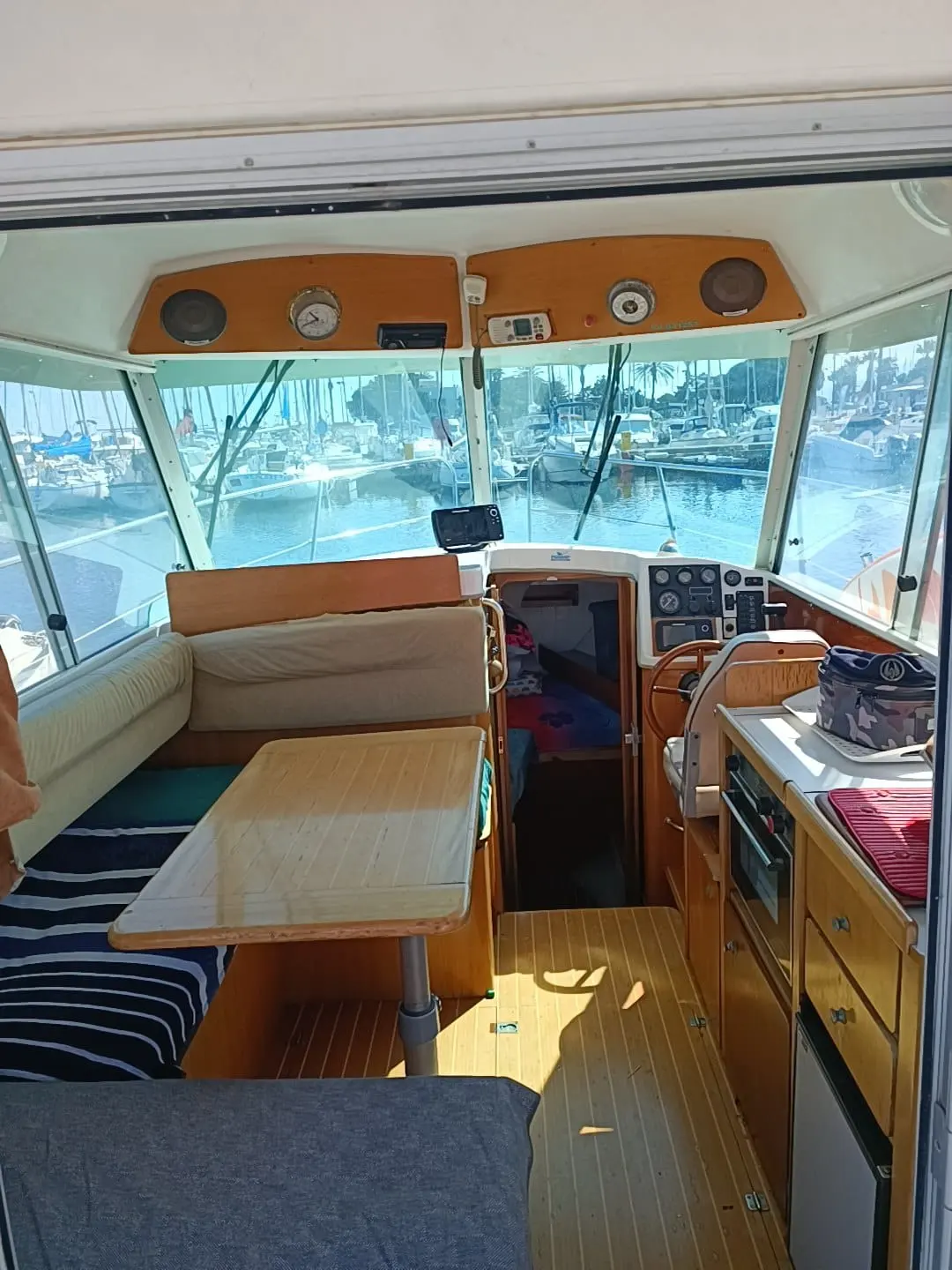 Ocqueteau 760 — Vue intérieure du carré et du poste de pilotage d’un bateau amarré au port.