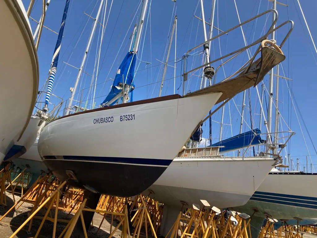 Olympic Carter 33 — Voiliers blancs sur bers dans un chantier naval, dont un marqué CHUBASCO B75231.