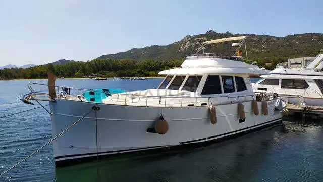 Sasga Menorquin 54 — Bateau à moteur blanc vu de trois quarts dans une baie, amarré au ponton.