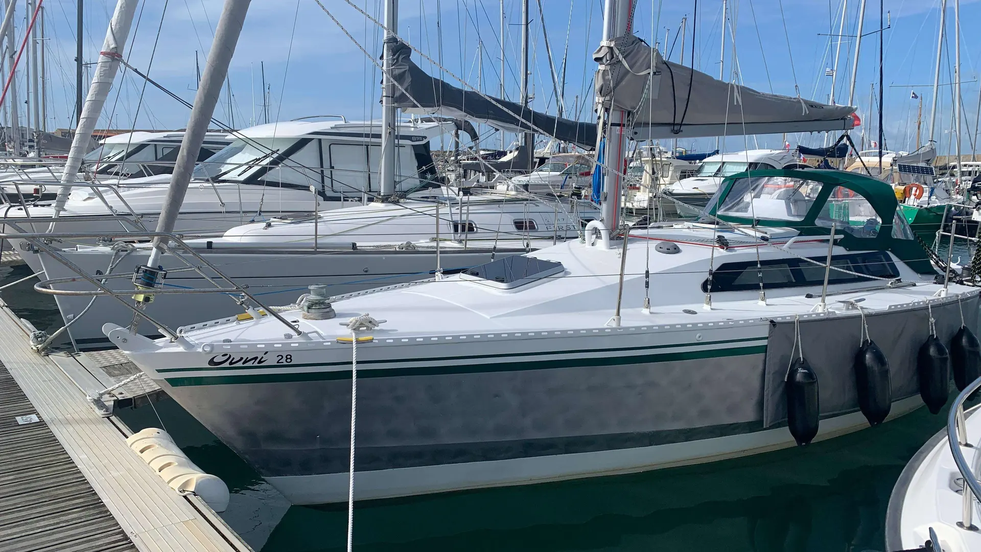 Alubat Ovni 28 — Voilier gris amarré à un ponton, vu de trois quarts dans un port.