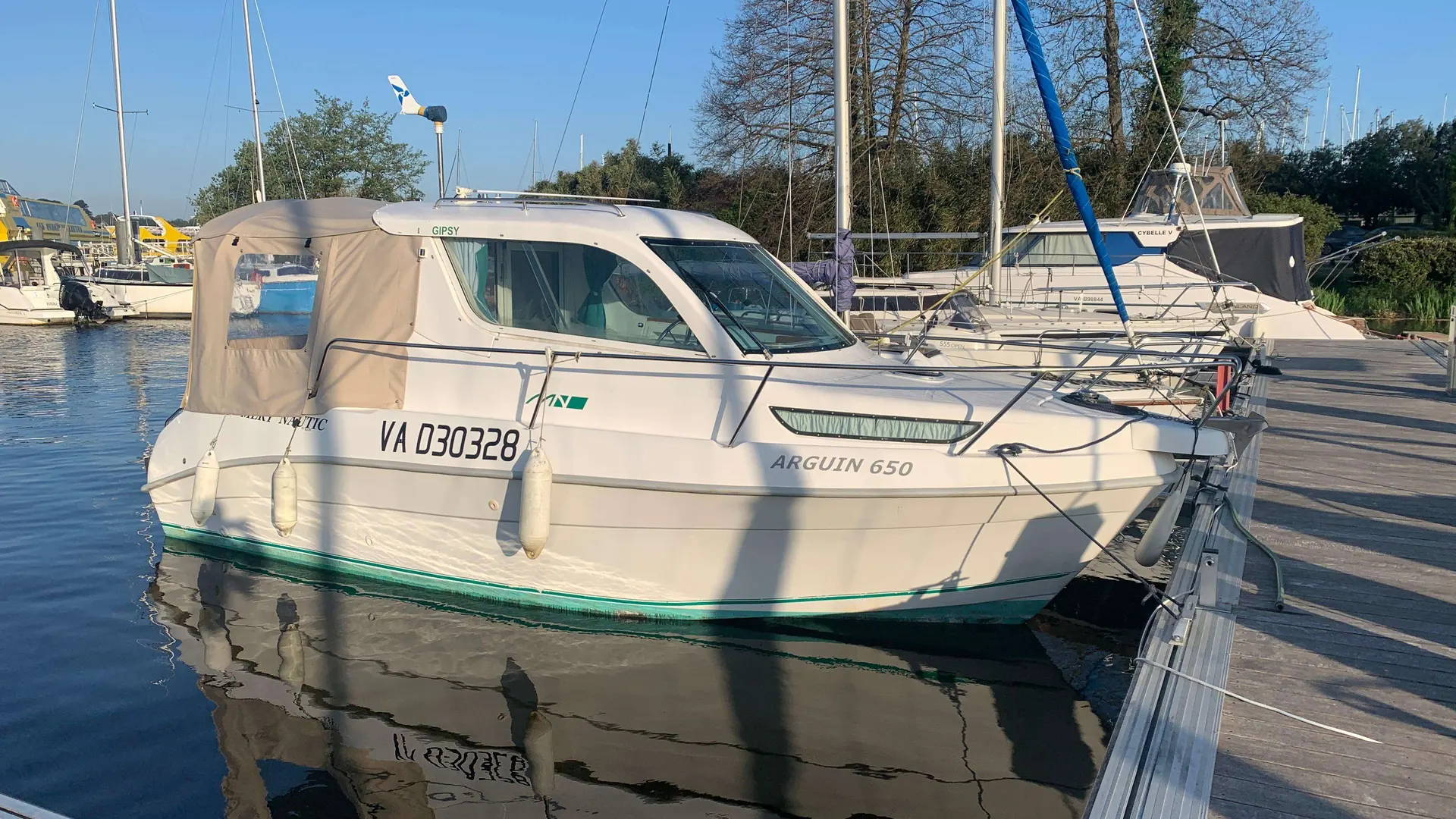 Mery Nautic Arguin 650 — Bateau à cabine blanche amarré à un ponton, photographié de trois quarts.