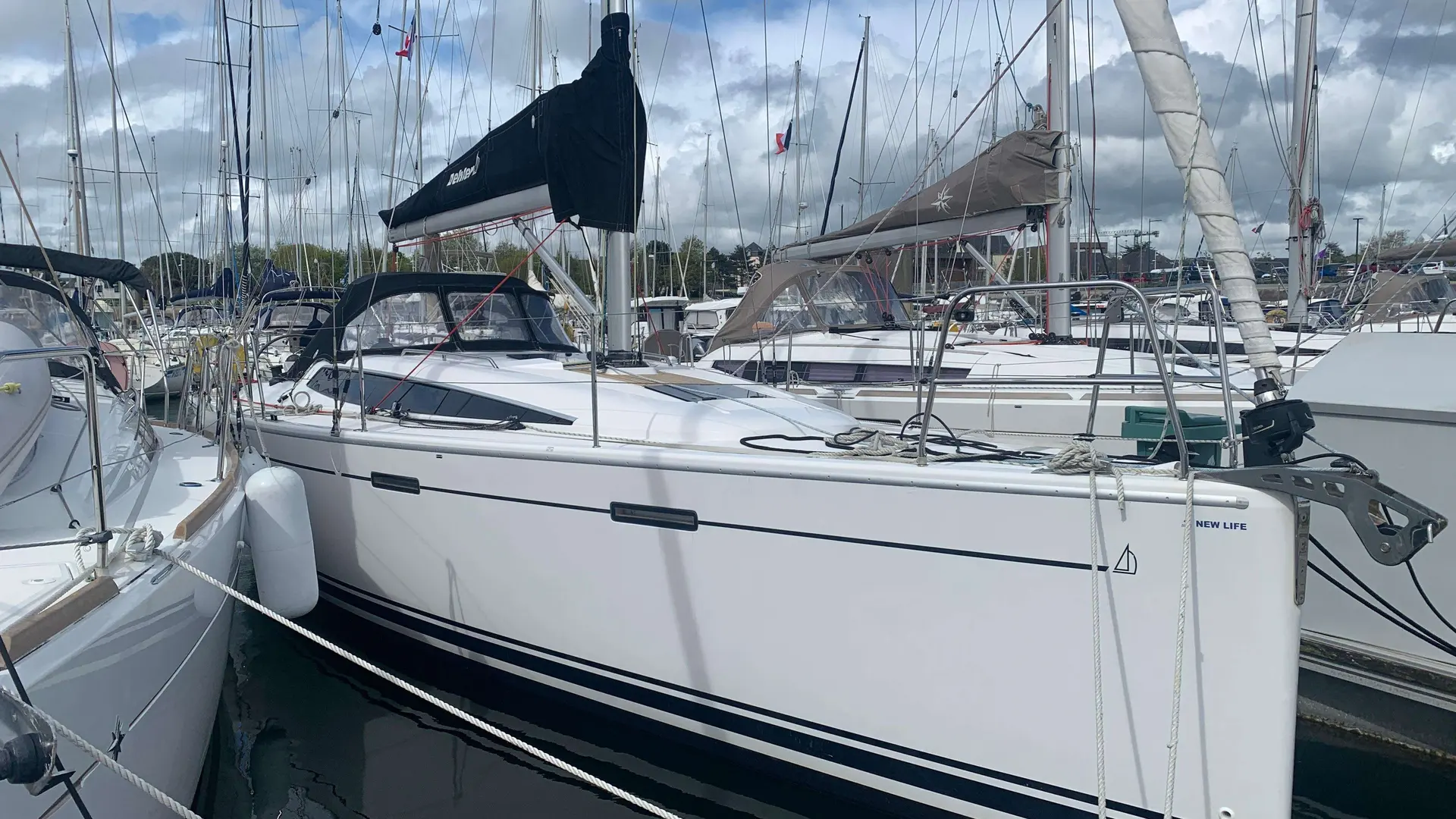 Dehler 38 — Voilier blanc amarré dans une marina, entouré d'autres bateaux.