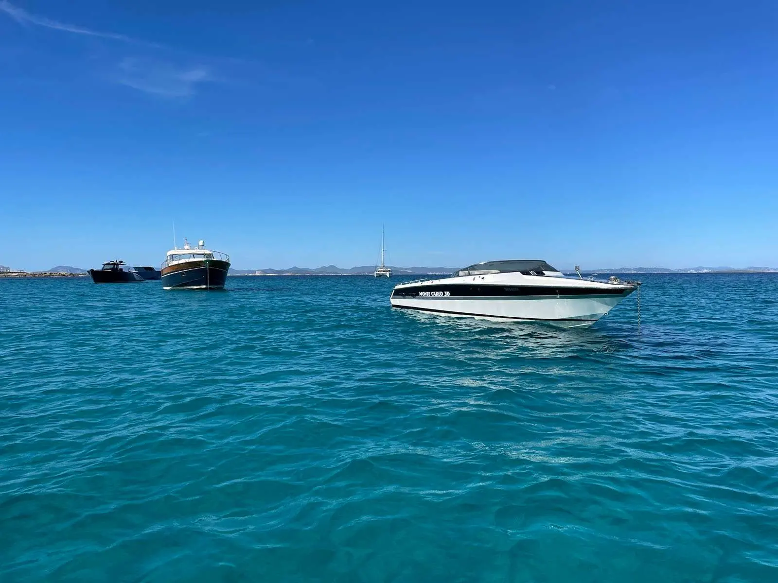 Monte Carlo Offshorer 30 — Bateau à moteur blanc et noir au mouillage, vu de profil sur une mer turquoise.