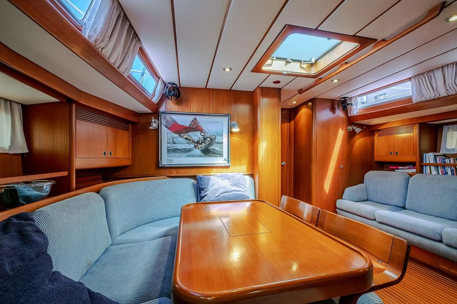Nautor Swan Swan 57 — Carré intérieur en bois avec salon, table à manger et panneaux ouvrants.