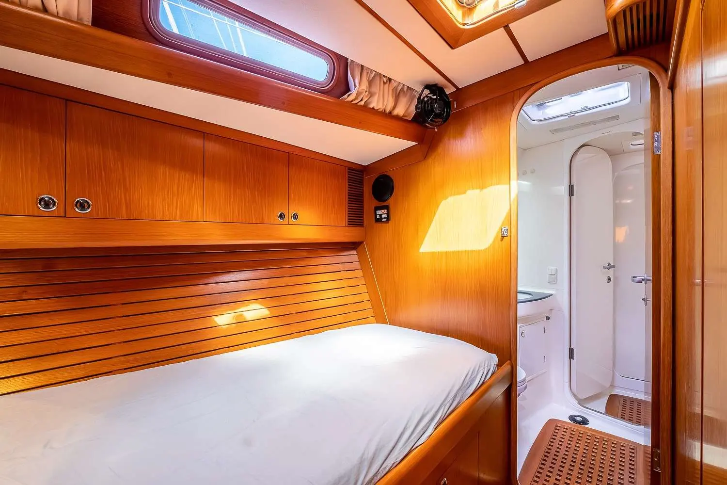 Nautor Swan Swan 57 — Cabine avec lit double, rangements en bois et accès à une salle d’eau.