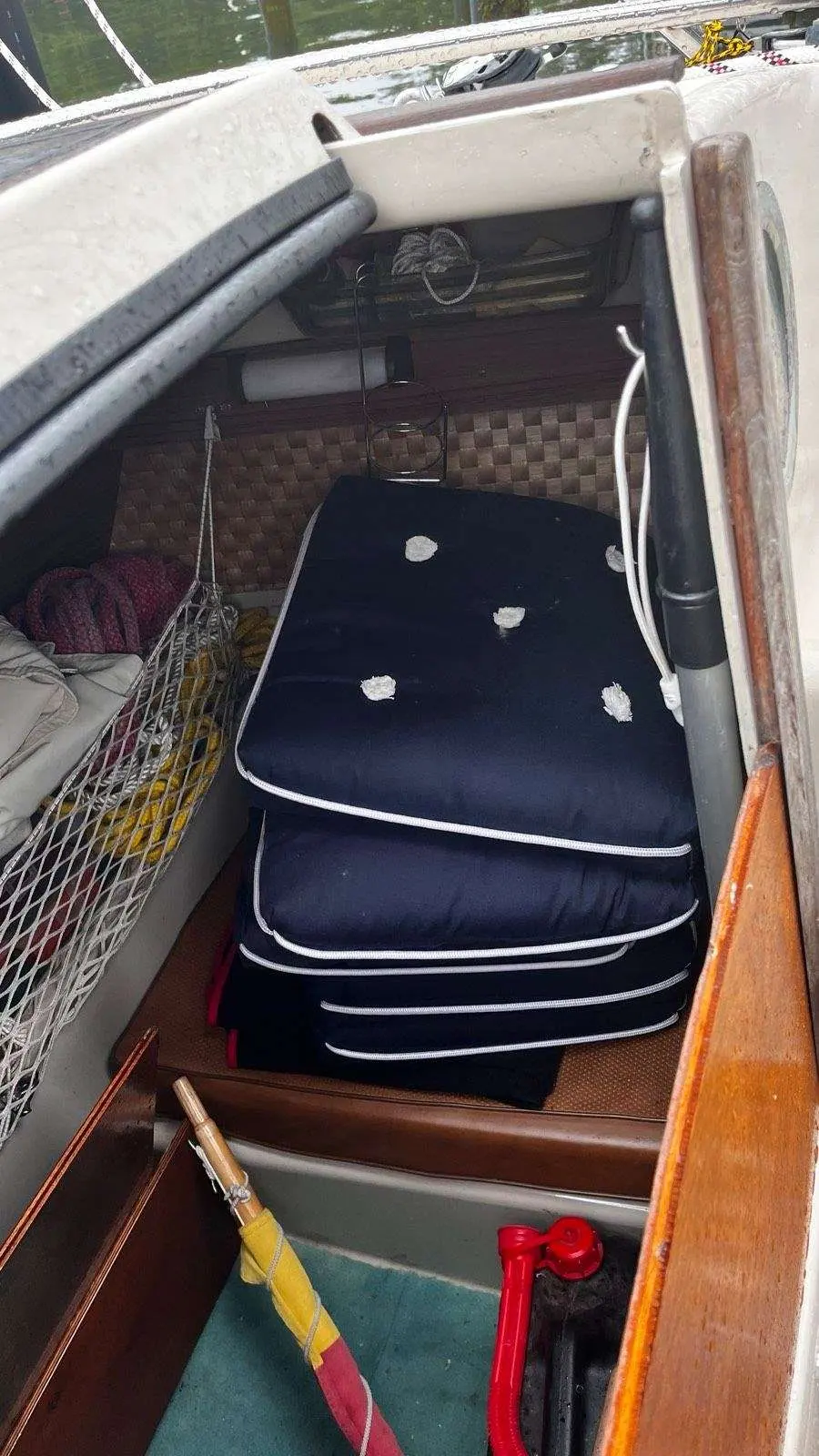 Dehler Delanta 76 — Une couchette intérieure encombrée de coussins et d'équipements divers.