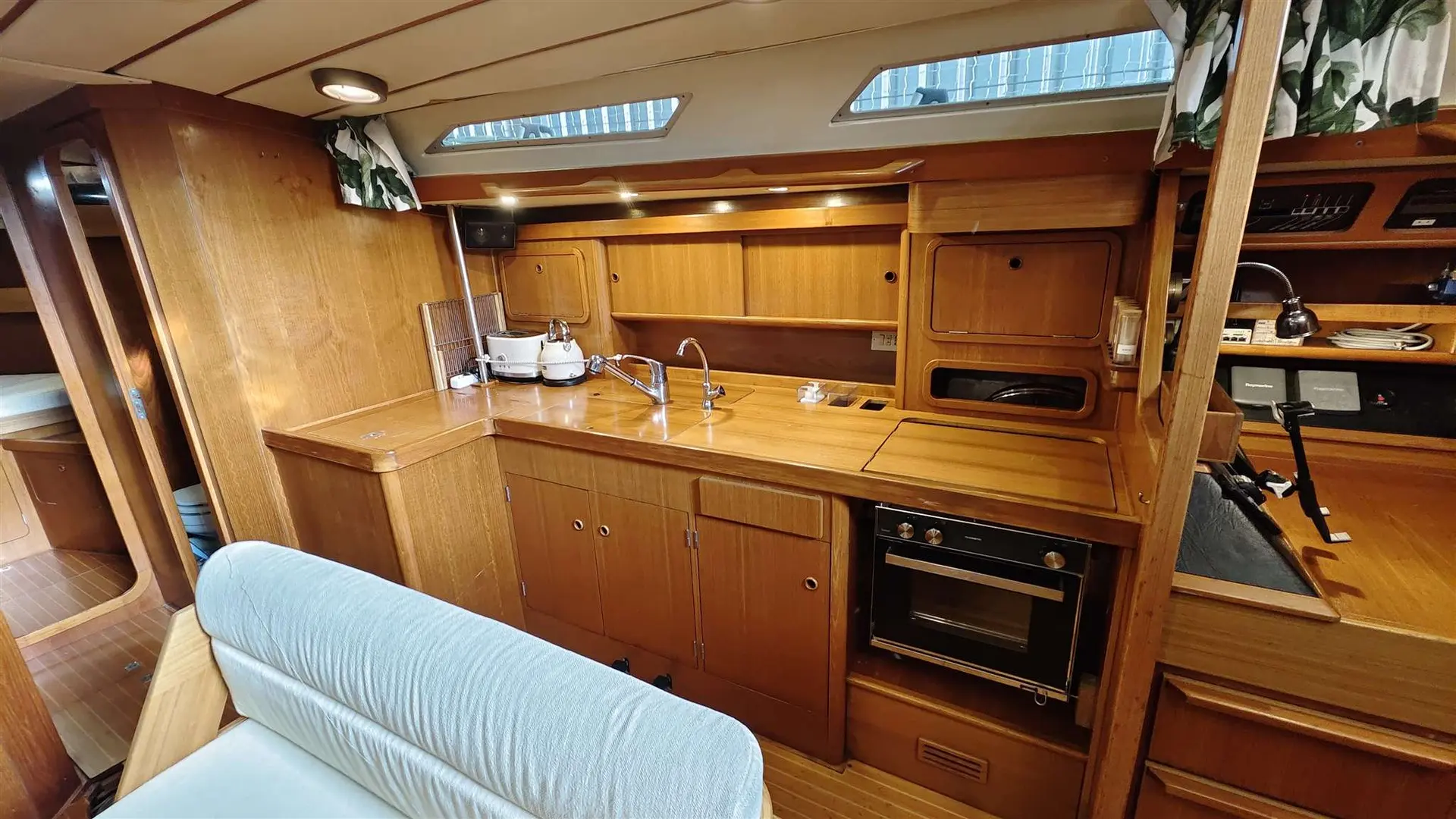 Grand Soleil 45 — Cuisine intérieure en bois avec évier, plan de travail, réfrigérateur et four.
