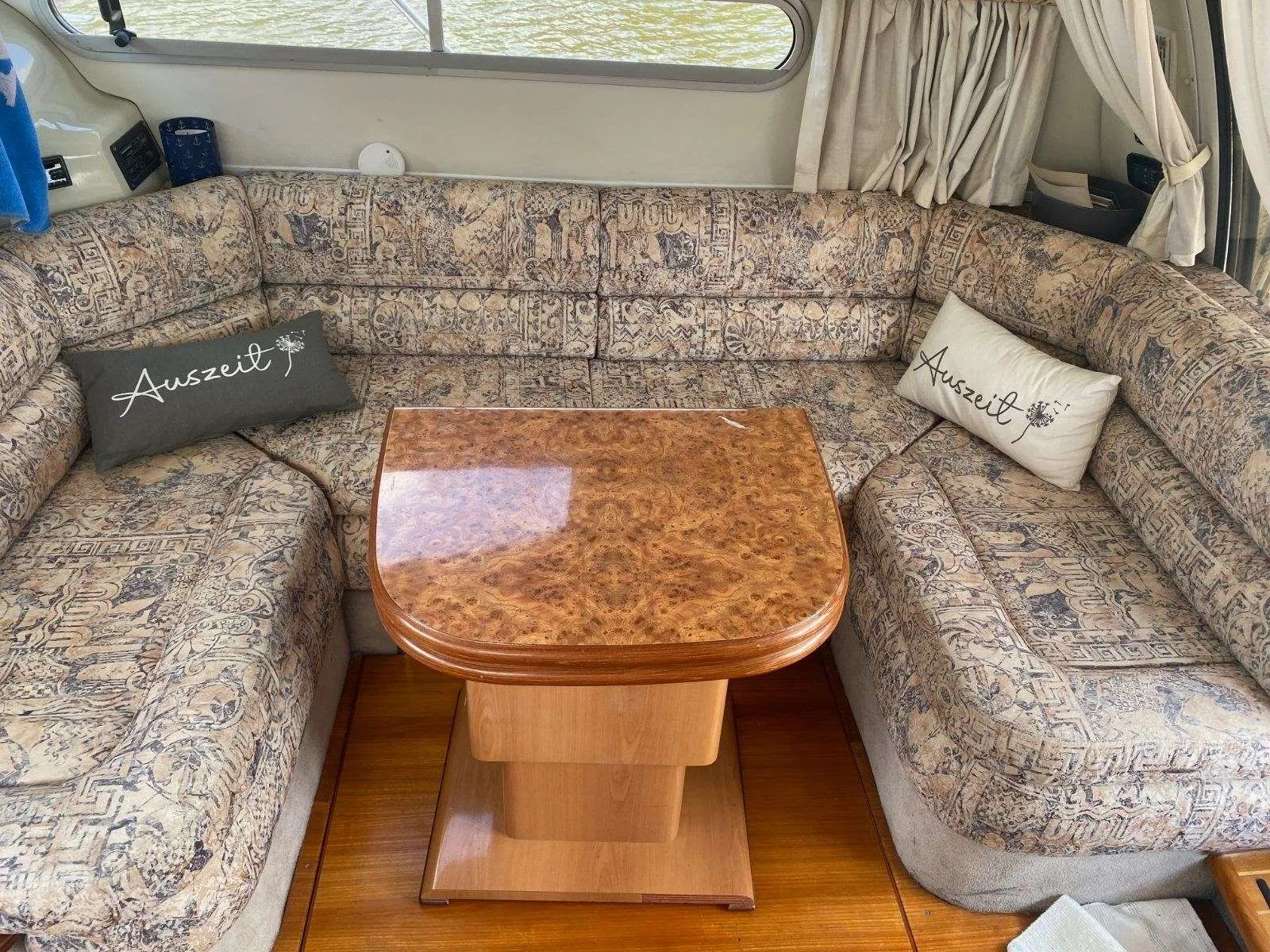 Sealine 360 — Salon intérieur avec banquettes en vis-à-vis et table centrale en bois.