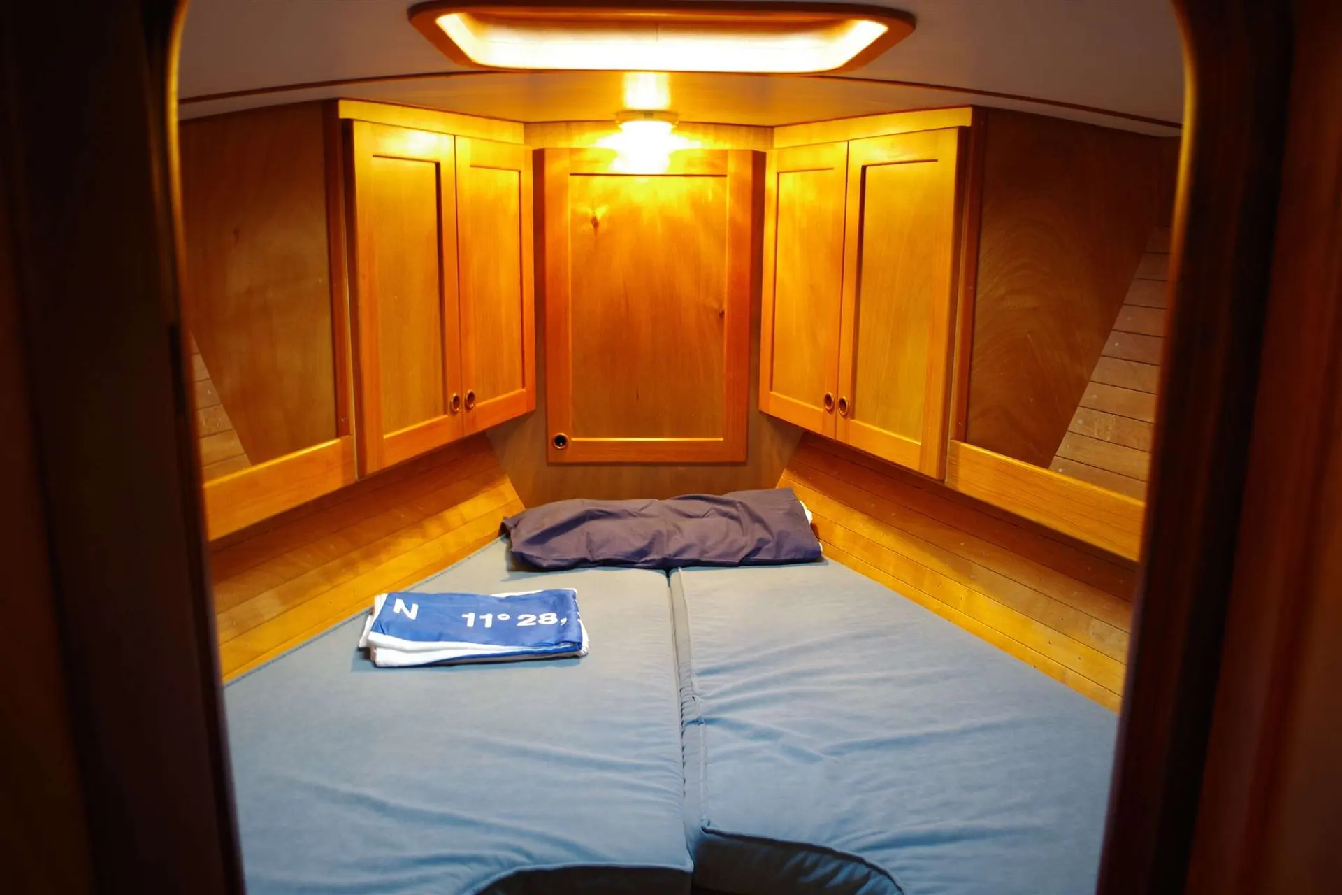 Feltz Skorpion II — Vue intérieure d'une cabine avant avec couchette double et rangements en bois.