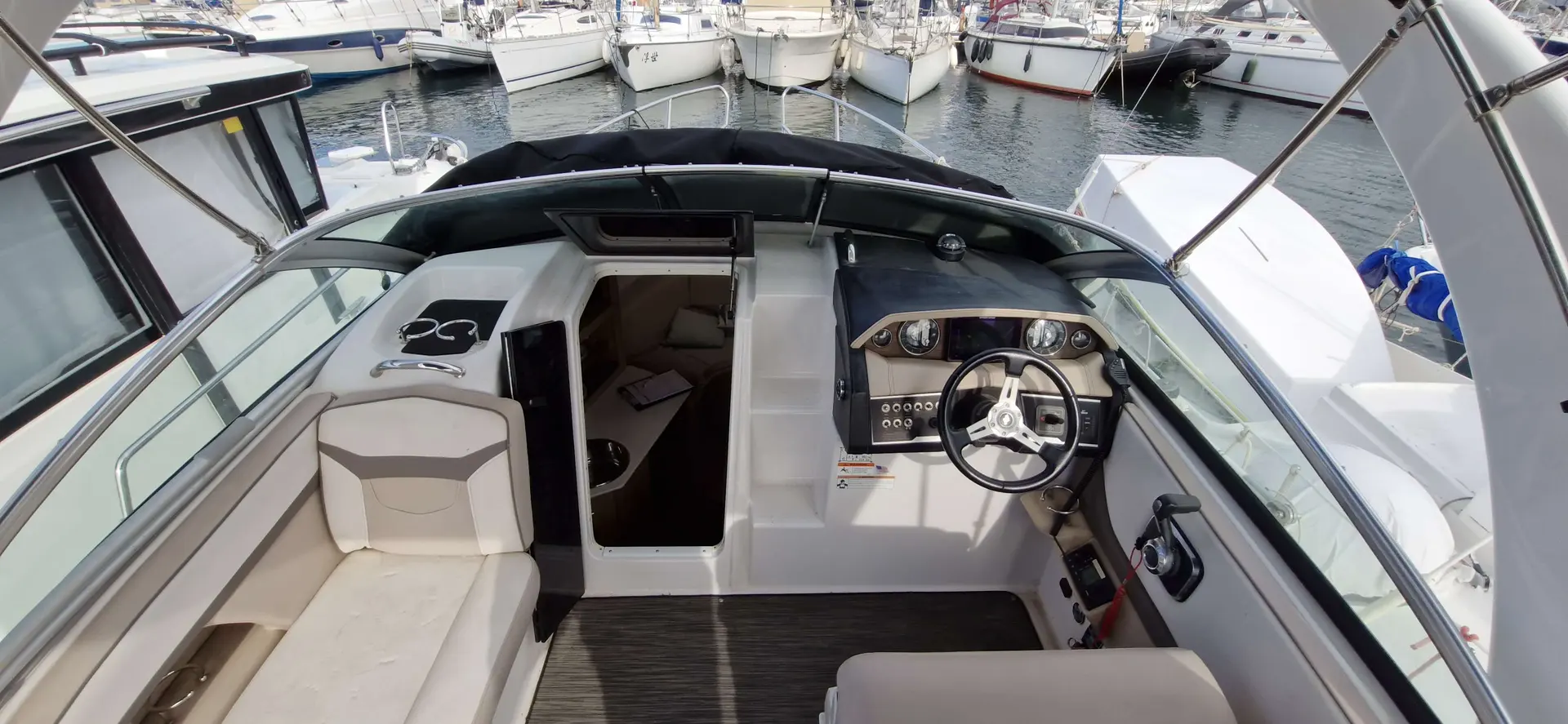 Four Winns V 255 — Vue du cockpit et du poste de pilotage d’un bateau amarré en marina.