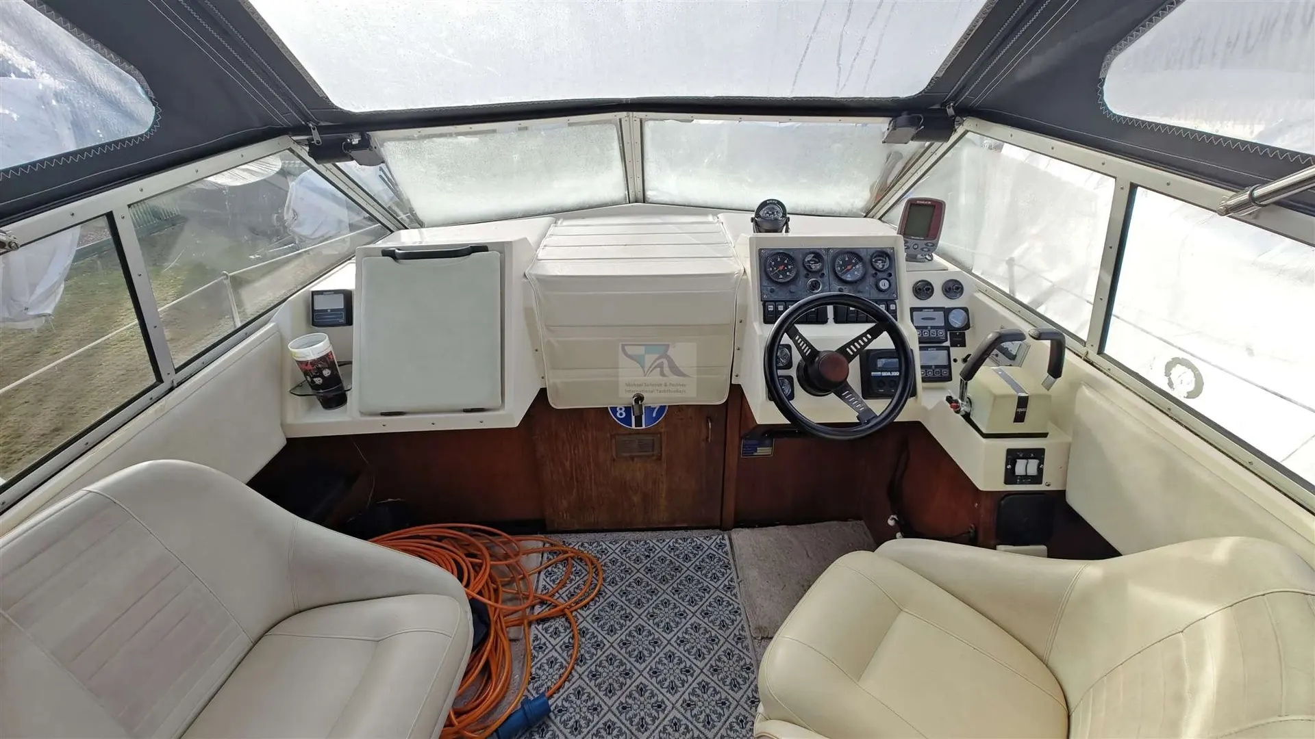 Fjord 725 — Vue du poste de pilotage intérieur d’un bateau, avec volant, instruments et sièges.