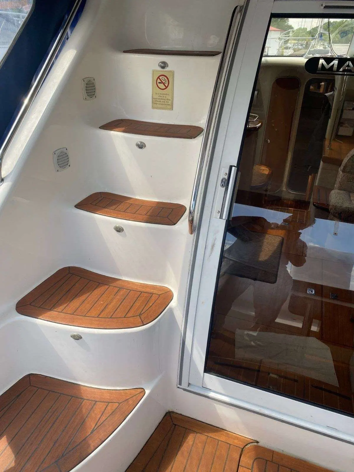 Sealine 360 — Escalier intérieur menant à la cabine d’un bateau, avec marches en teck.