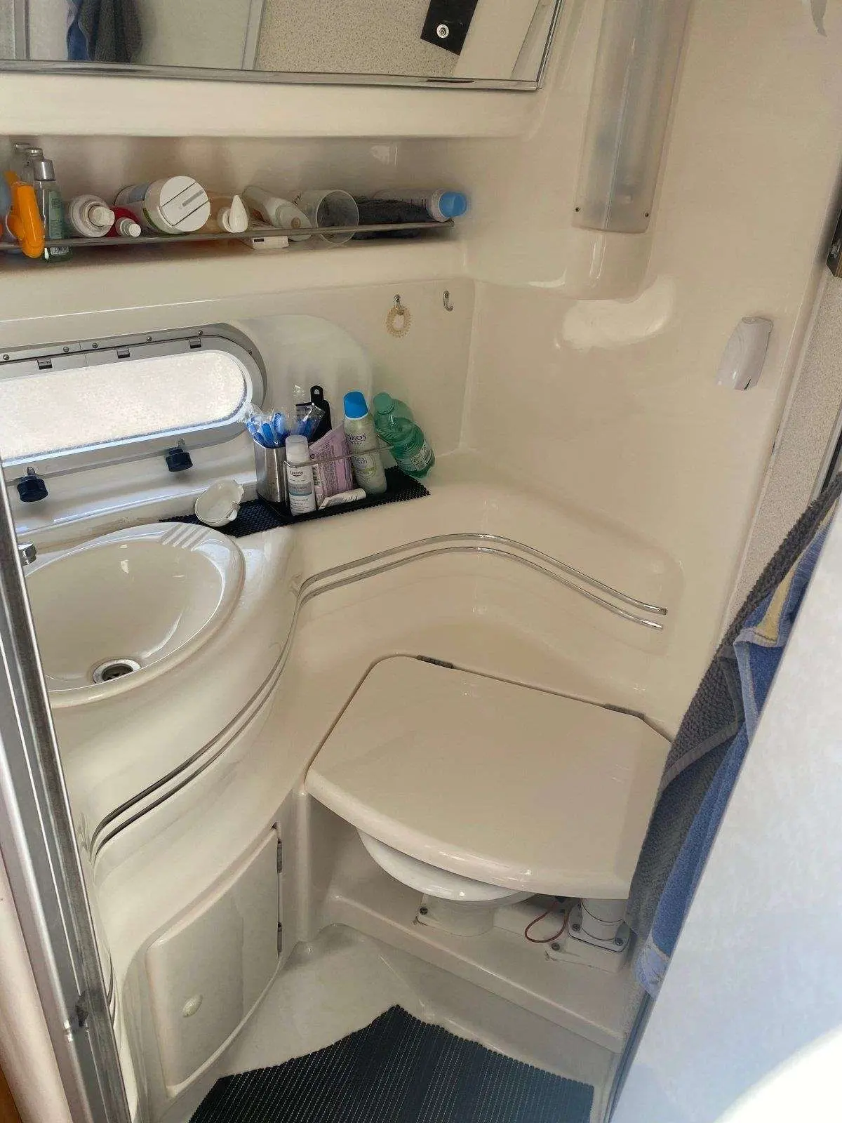 Sealine 360 — Salle de bains avec lavabo, toilettes, miroir et produits de toilette.