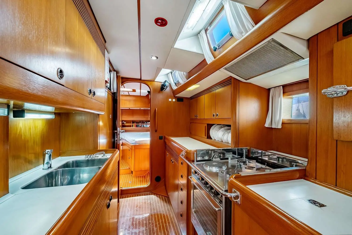 Nautor Swan Swan 57 — Vue de la cuisine en bois, avec évier, rangements et appareils de cuisson.