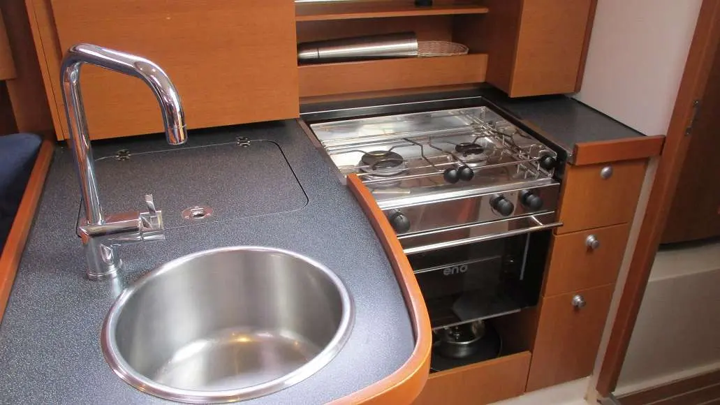 Hanse 325 — Cuisine intérieure avec évier, robinet et cuisinière à gaz.