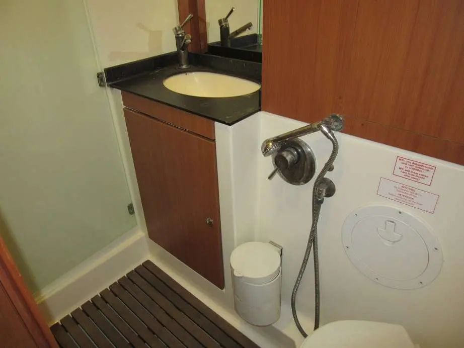 Bavaria 55 Cruiser — Salle d’eau avec lavabo, douchette, toilettes et rangements en bois.