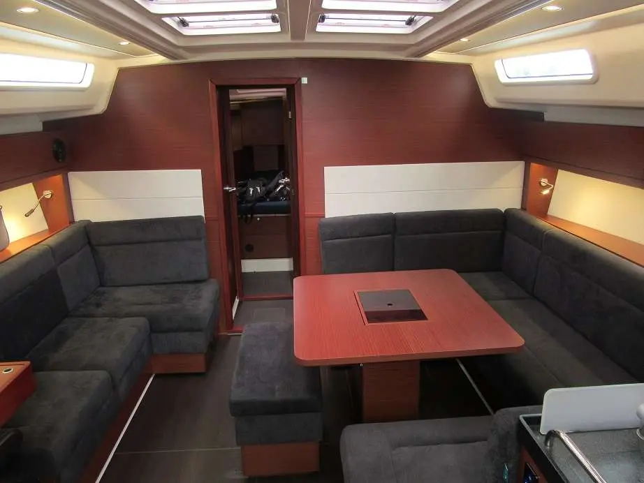 Hanse 458 — Carré intérieur avec banquettes, table centrale et éclairage naturel.
