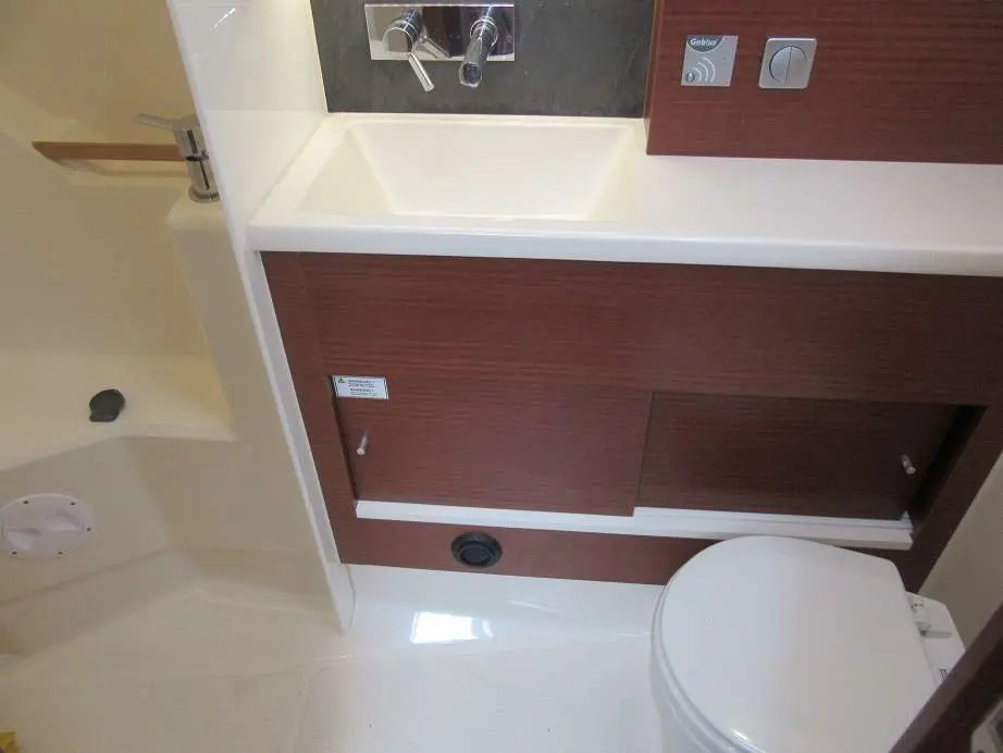 Hanse 458 — Salle d’eau avec lavabo, rangements en bois et toilettes à bord.