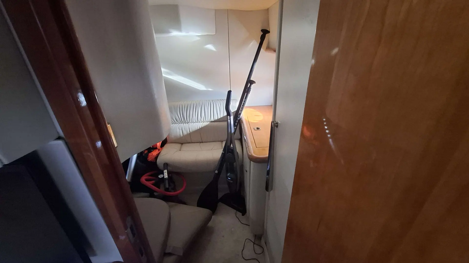 Sunseeker Portofino 400 — Vue partielle d'une cabine avec banquette, rangements et équipements posés au sol.