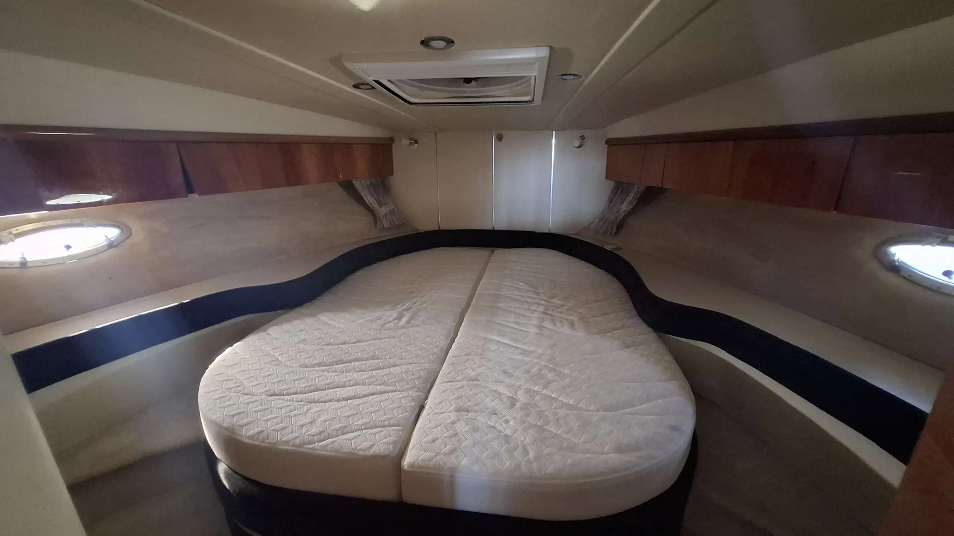 Sunseeker Portofino 400 — Cabine avant avec lit double, rangements en bois et hublots latéraux.