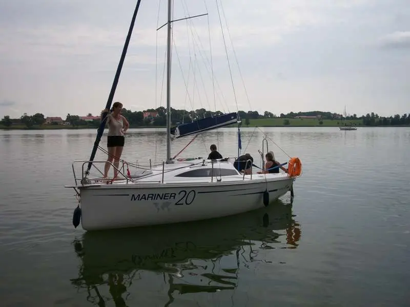 Mariner Yachts 20 — Voilier blanc photographié de trois quarts sur un plan d’eau, avec trois personnes à bord.