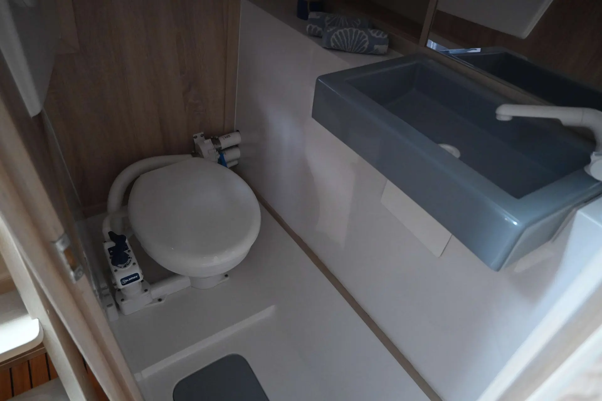 Viko Boats Viko S26 — Salle d’eau d’un bateau avec toilettes et lavabo à bac bleu.