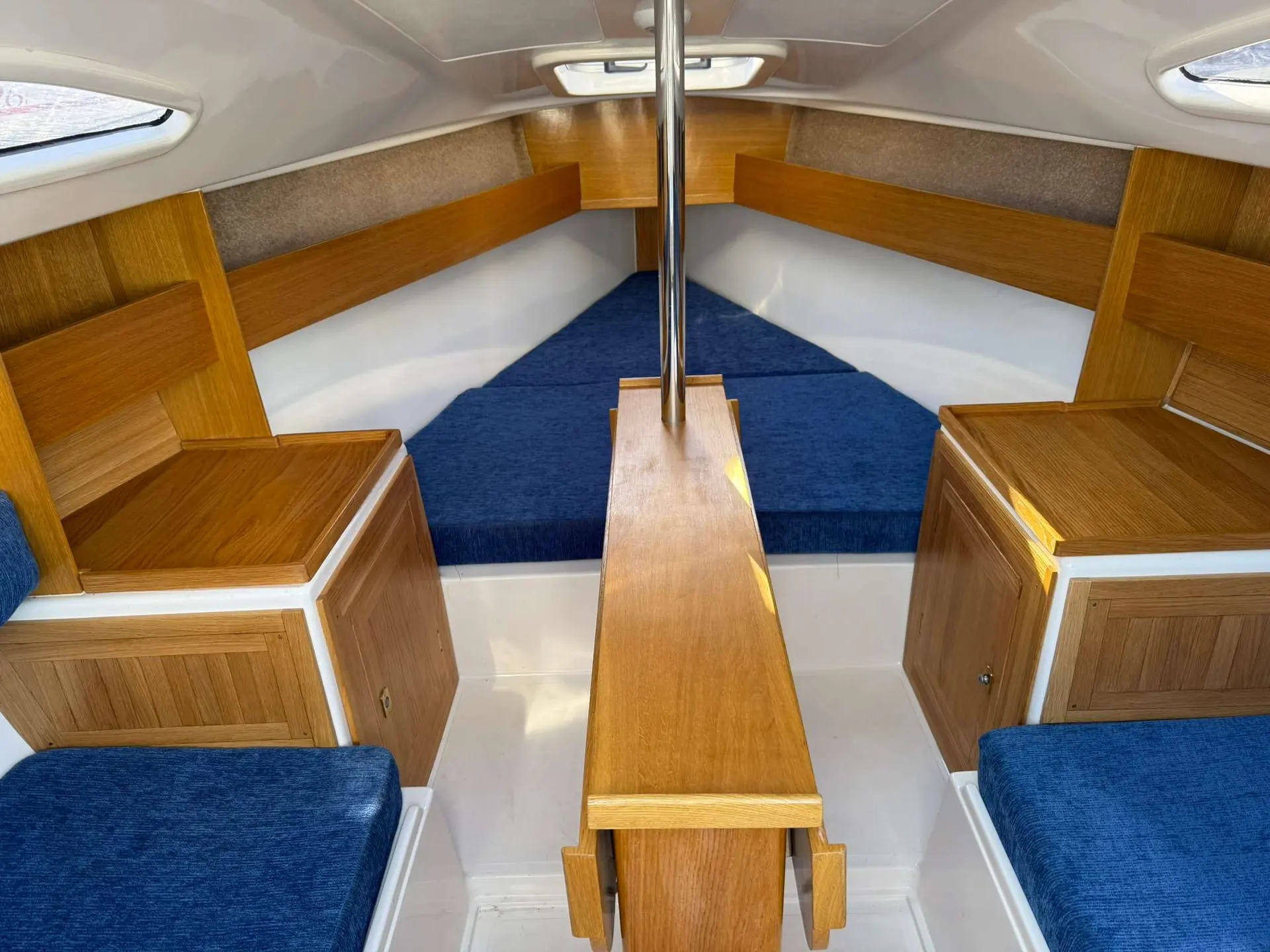 Mariner Yachts 20 — Vue de la cabine avant, avec couchettes bleues et aménagements en bois.