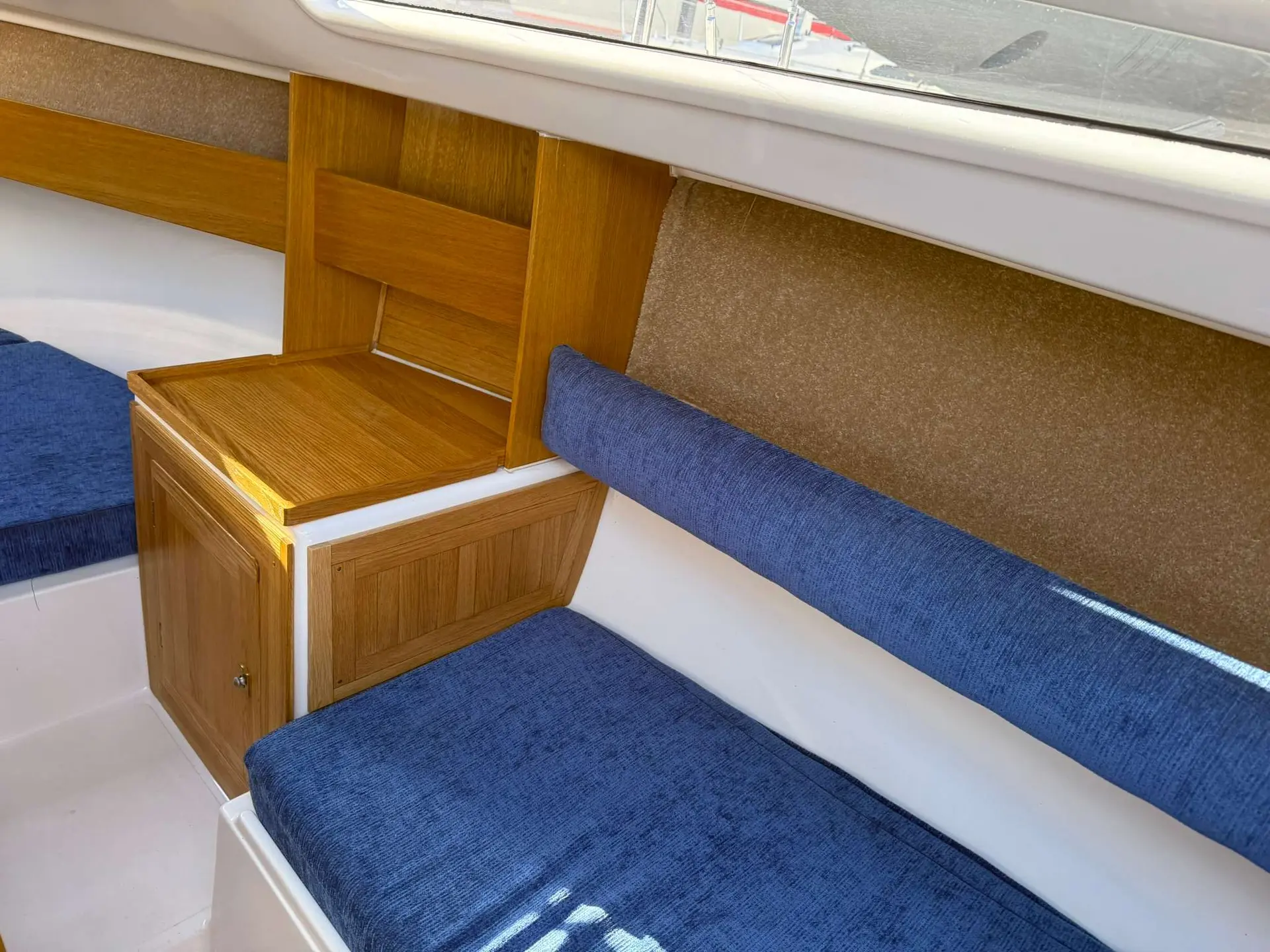 Mariner Yachts 20 — Banquette intérieure bleue et rangement en bois à bord du bateau.