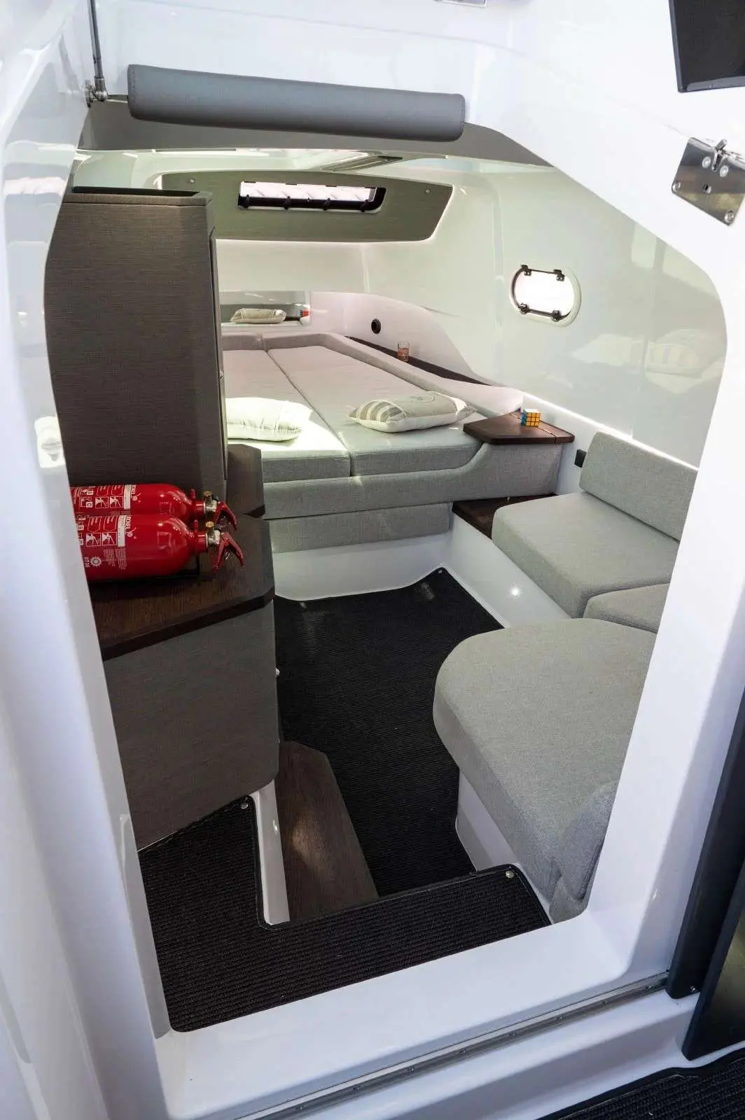 Axopar 37 XC Cross Cabin — Cabine avant avec couchette, assises et extincteurs visibles.