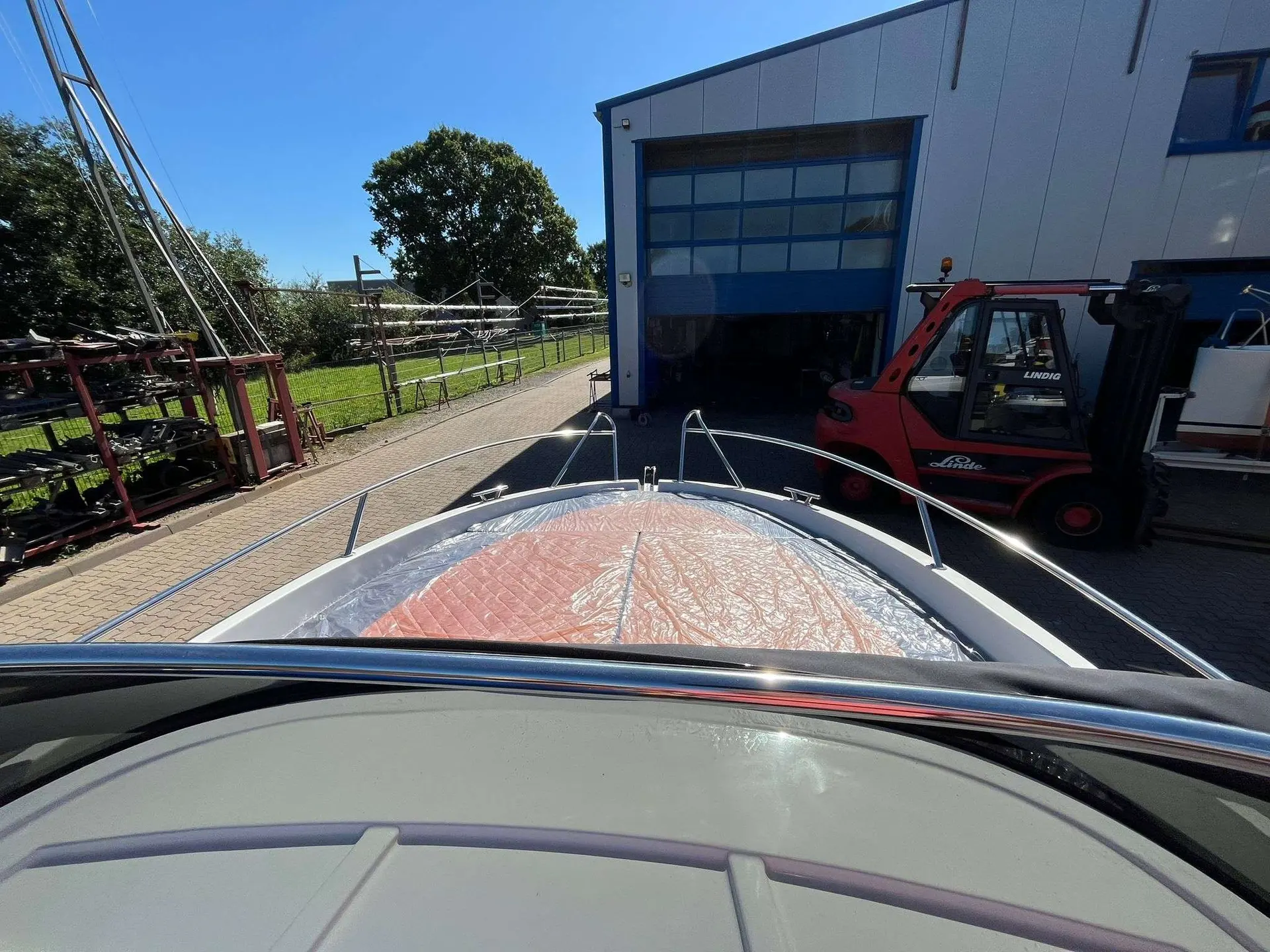 Marine Time QX 620 — Vue depuis le cockpit vers la proue couverte d’un bateau, devant un bâtiment industriel.