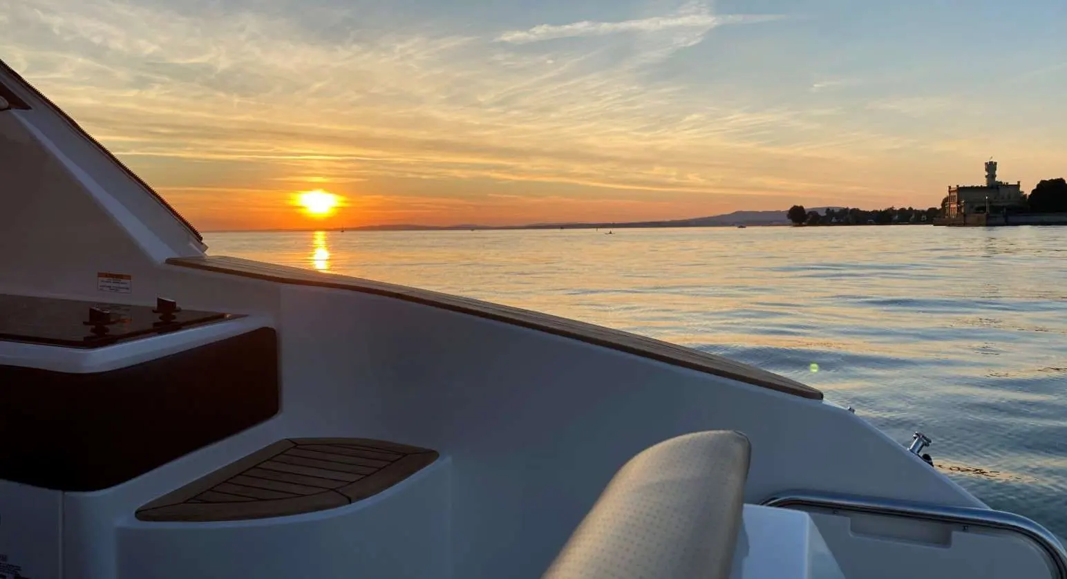 Sea Ray 320 DAE — Vue partielle de la proue d’un bateau sur l’eau au coucher du soleil.