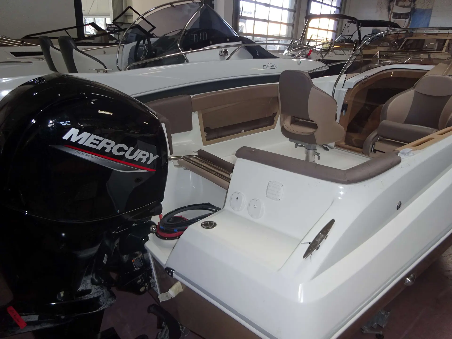 Galia 570 Sun Deck — Vue arrière d’un bateau exposé en intérieur, avec moteur hors-bord et cockpit.