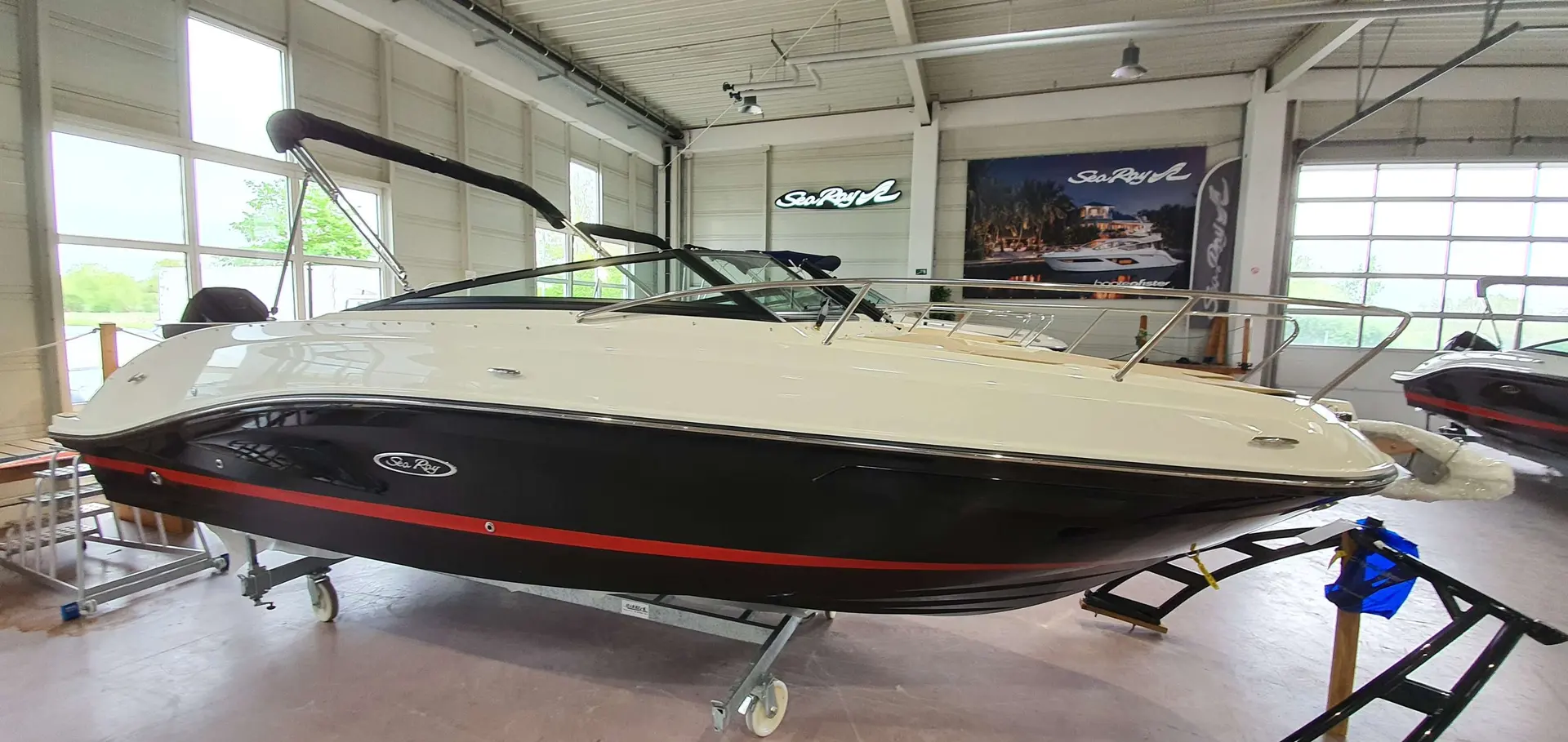 Sea Ray 230 SSOE — Bateau à coque noire et pont blanc exposé dans un showroom.