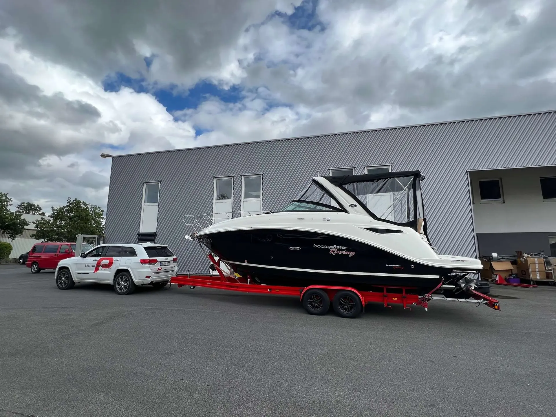 Sea Ray 265 DAE — Bateau à moteur blanc et noir sur remorque devant un bâtiment industriel.