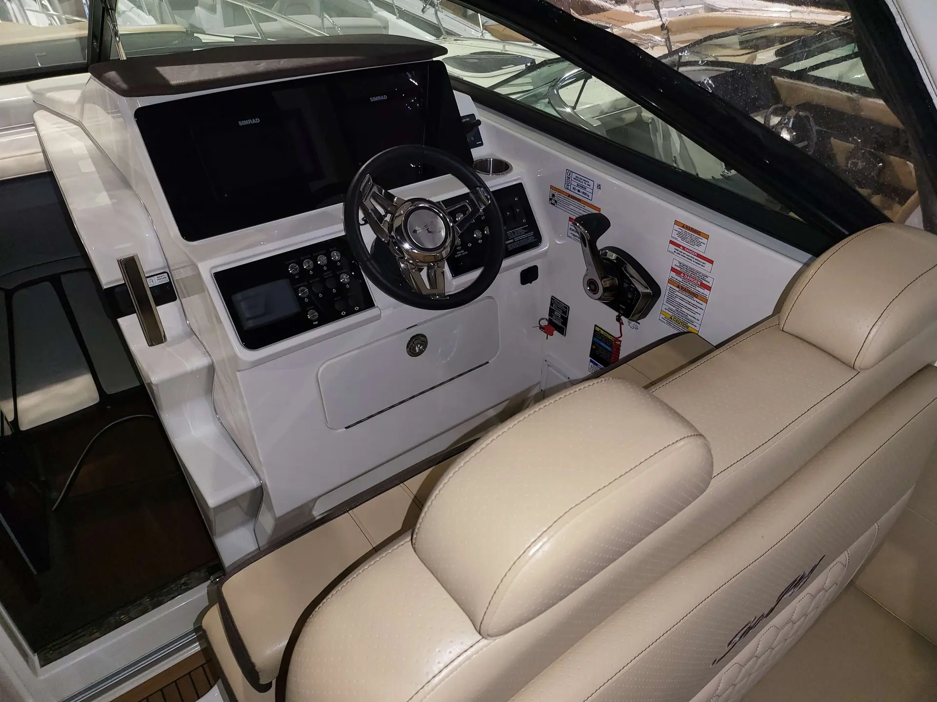 Sea Ray 265 DAE — Vue du poste de pilotage avec écran, volant, commandes et banquette.