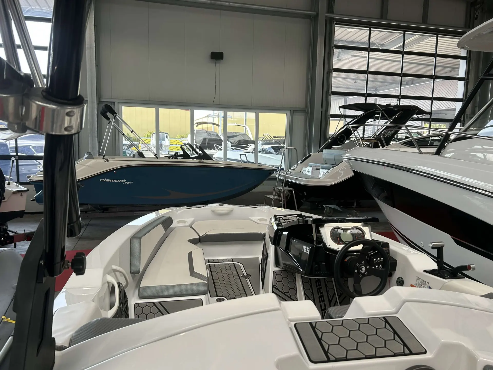Scarab Boats Scarab 165 Gost — Vue du cockpit et du poste de pilotage d’un bateau exposé dans un showroom.