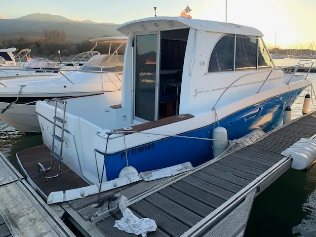 Beneteau Antares 760 — Vedette à coque bleue amarrée à un ponton, vue de trois quarts arrière.