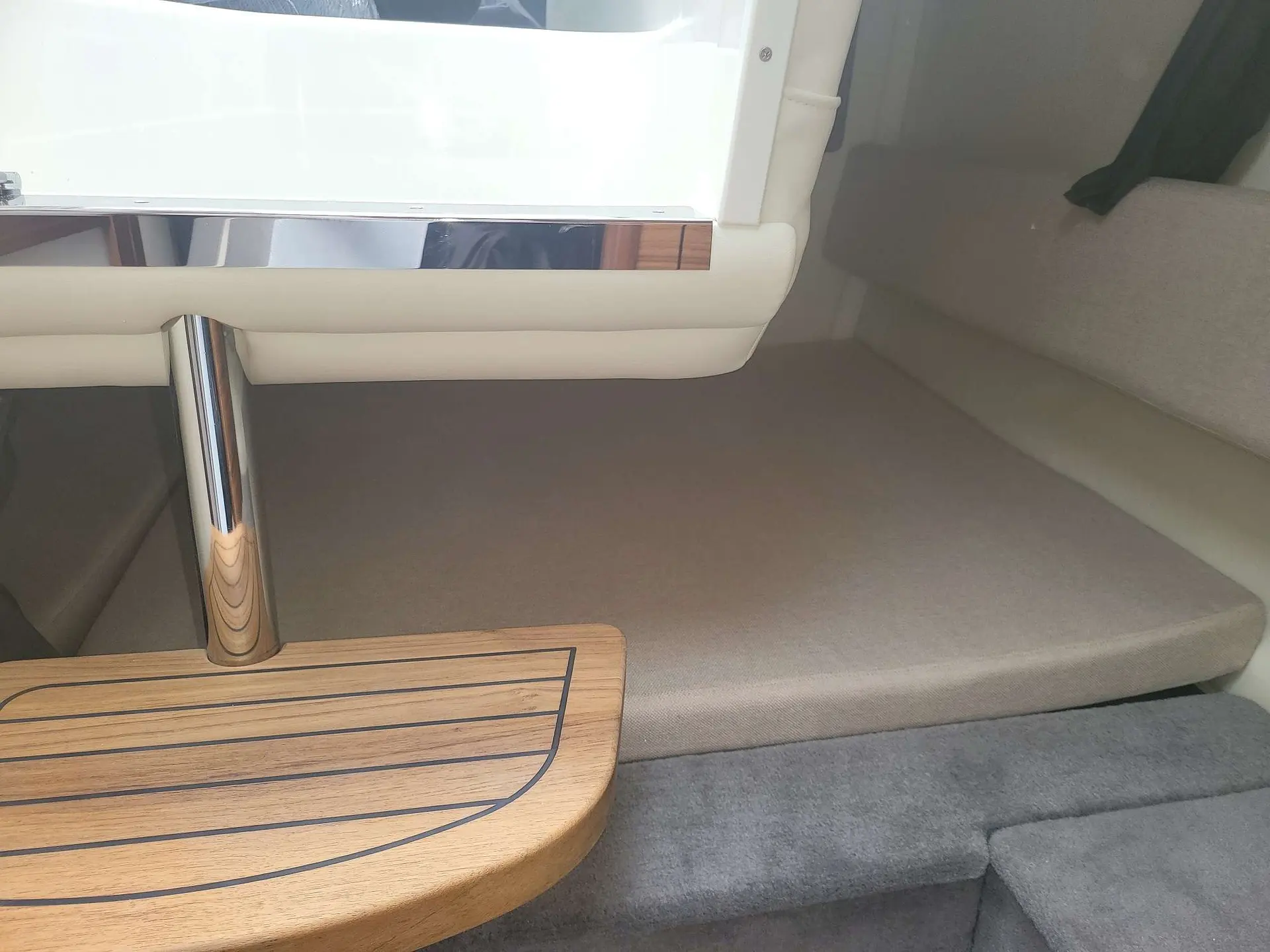 Sea Ray 265 Sundancer — Vue rapprochée d'une banquette et d'une table en bois dans la cabine du bateau.