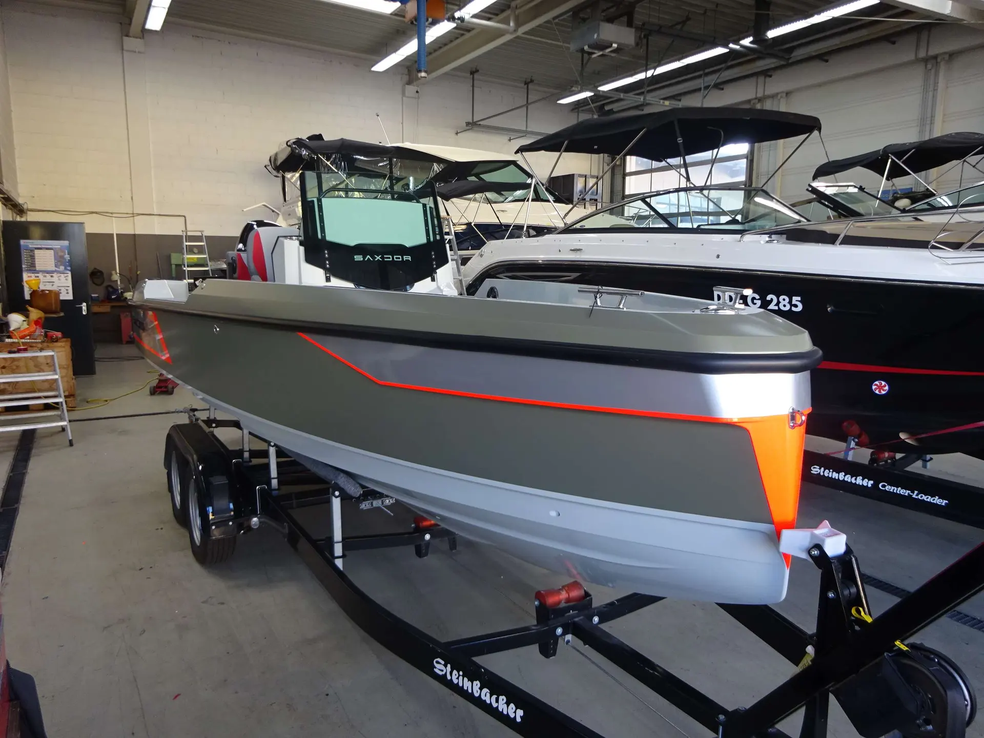 Saxdor 200 Pro Sport — Bateau à moteur gris et rouge présenté sur remorque dans un atelier.
