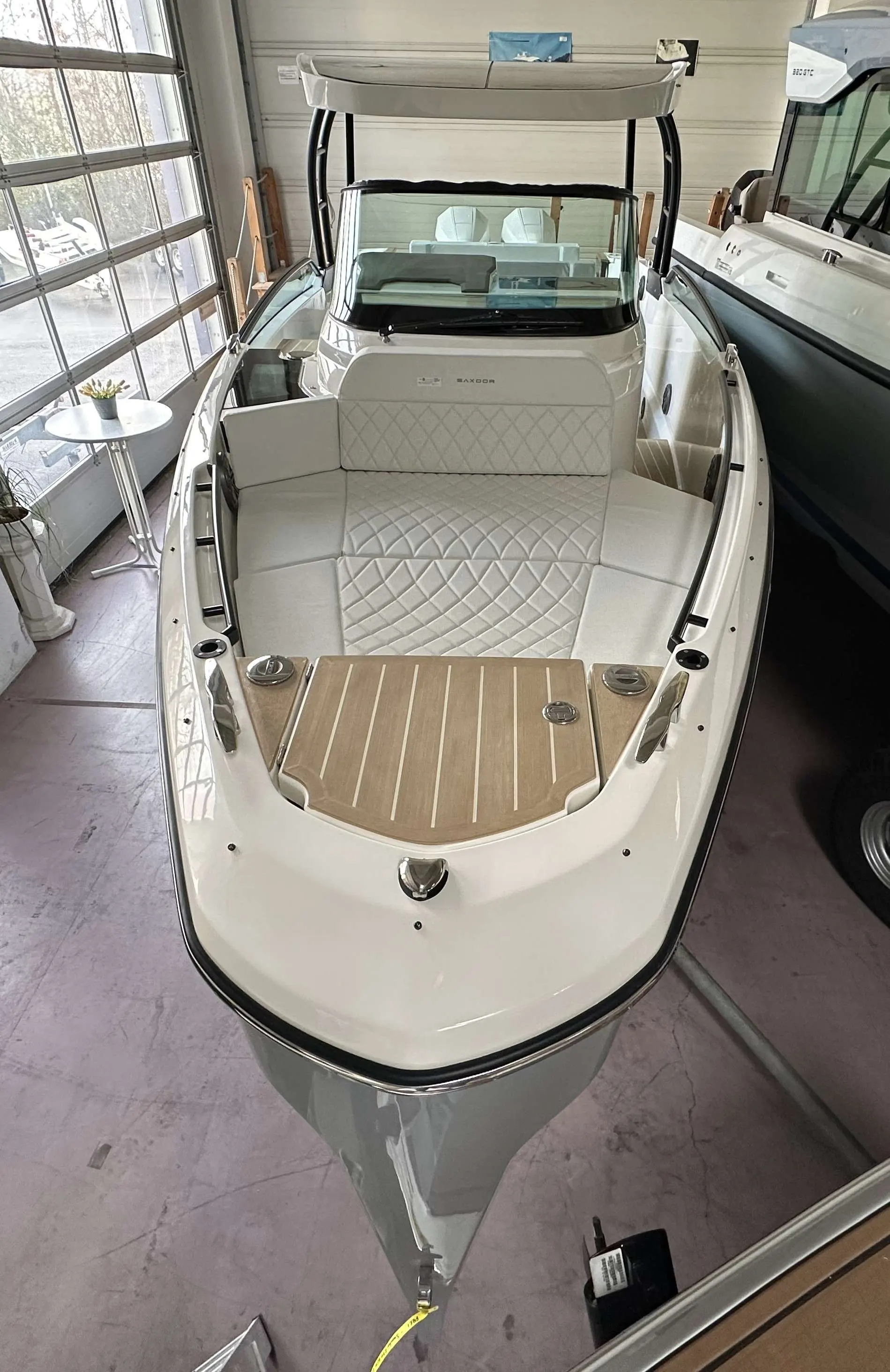 Saxdor 270 GTO — Vue intérieure de la partie avant d’un bateau, avec banquette capitonnée et pare-brise.