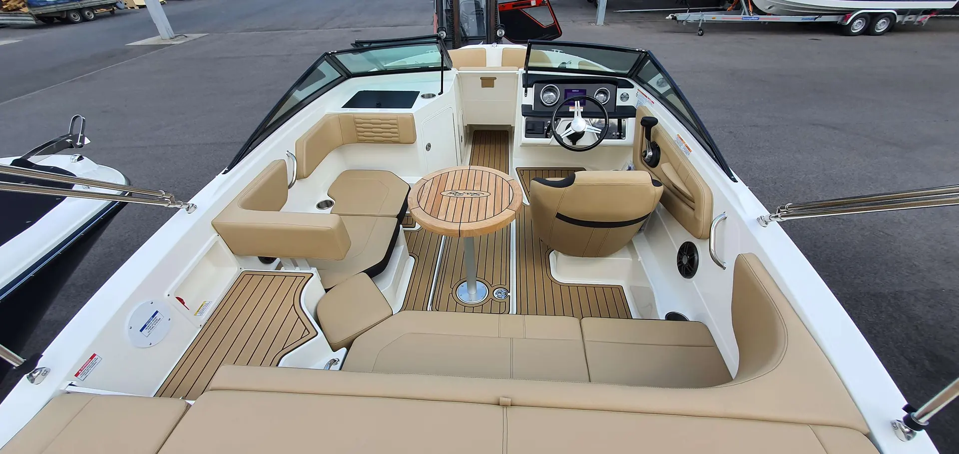 Sea Ray 190 SPXE — Vue plongeante du cockpit avec banquettes, table, poste de pilotage et taud.