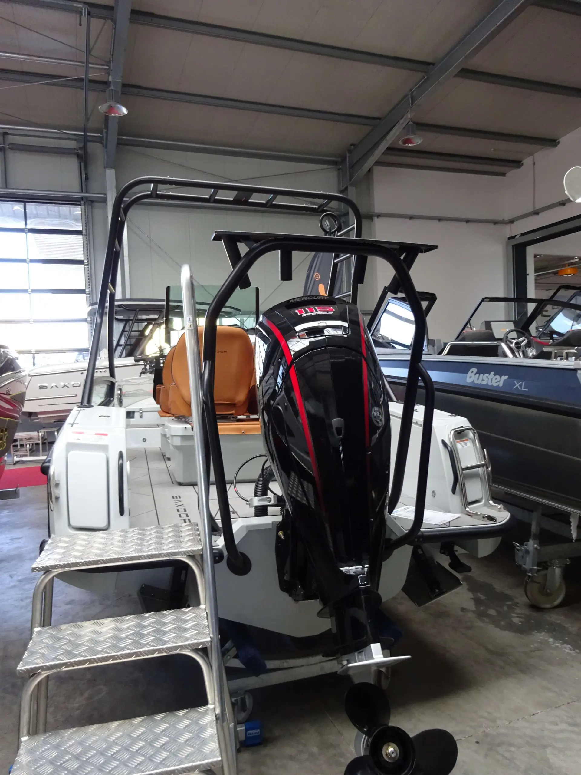 Saxdor 200 Pro Sport — Vue arrière d’un bateau à moteur exposé dans un hall, avec son moteur hors-bord visible.