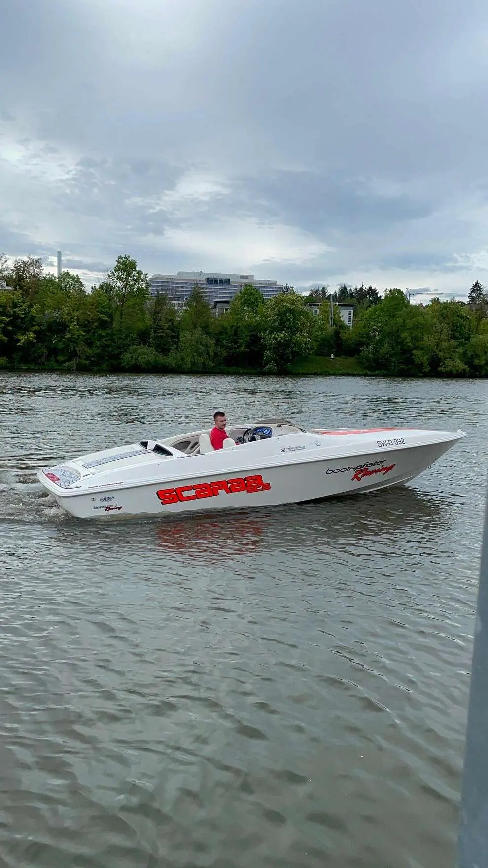 Scarab Boats Scarab — Bateau à moteur blanc naviguant sur une rivière, avec une personne à la barre.