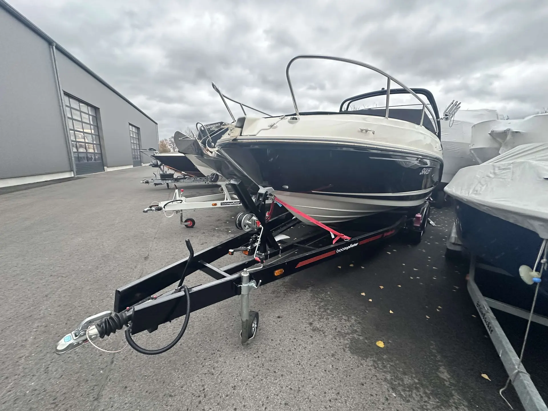 Sea Ray 230 SSE — Bateau à moteur sur remorque, stationné devant un bâtiment nautique.