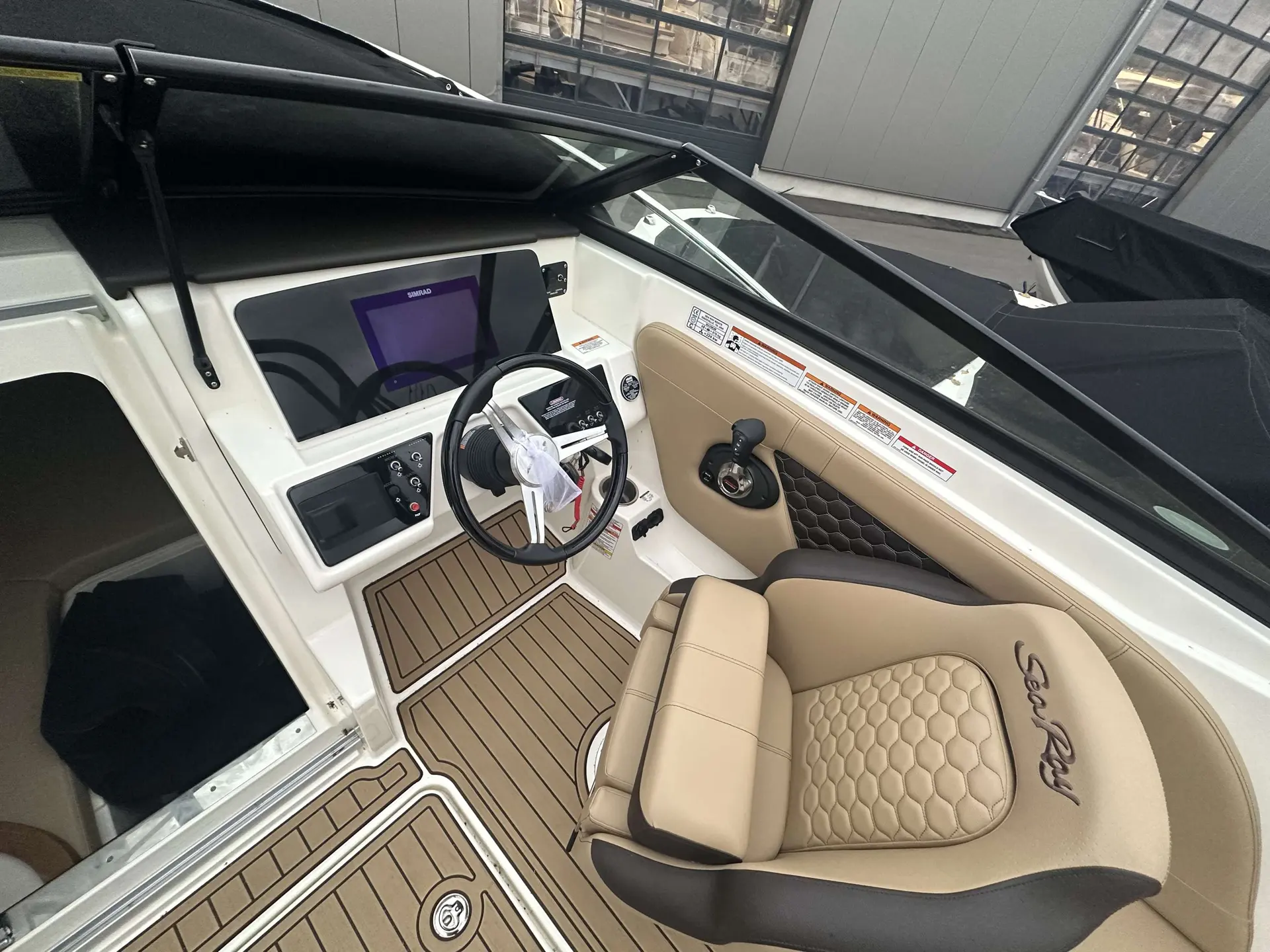 Sea Ray 230 SSE — Vue du poste de pilotage avec écran, volant, commandes et siège baquet.